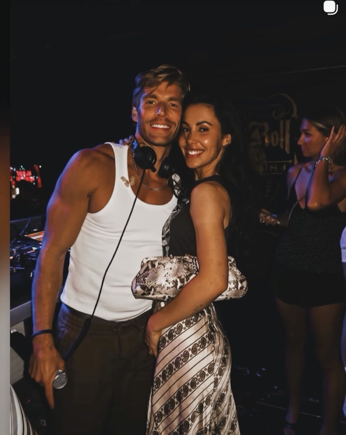 DJ and guest at a nightclub appearance — paisley print slip dress with a snakeskin clutch